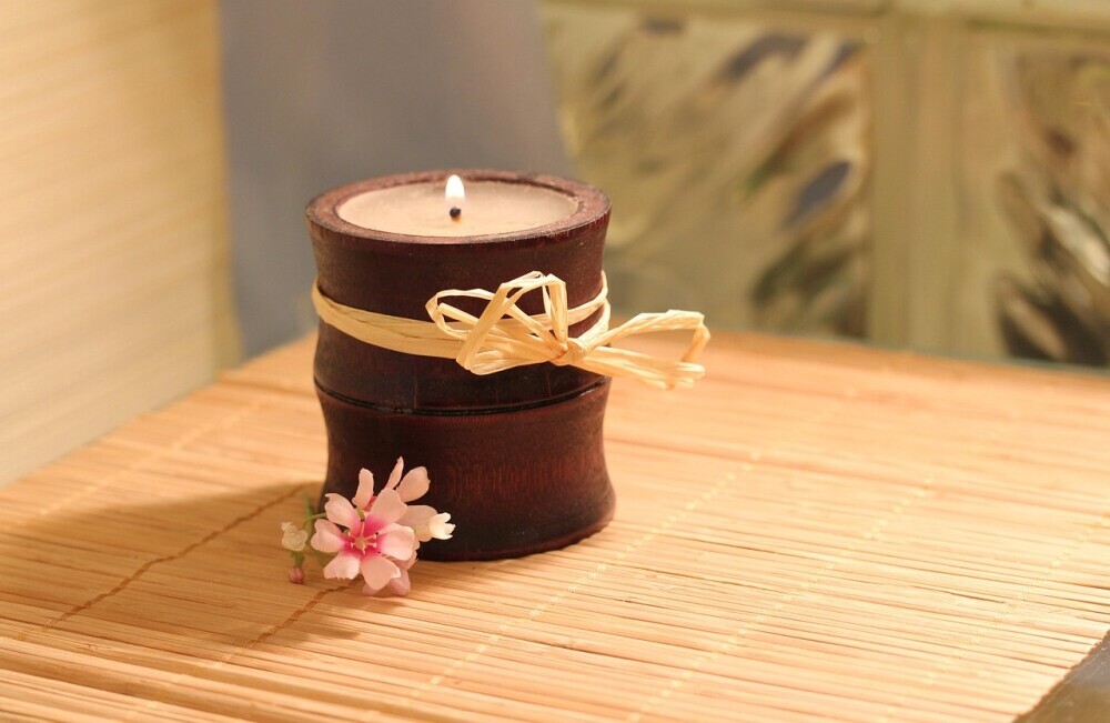 image of a lit candle and a small flower