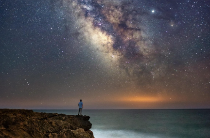 Man on a cliff looking at the Milky Way