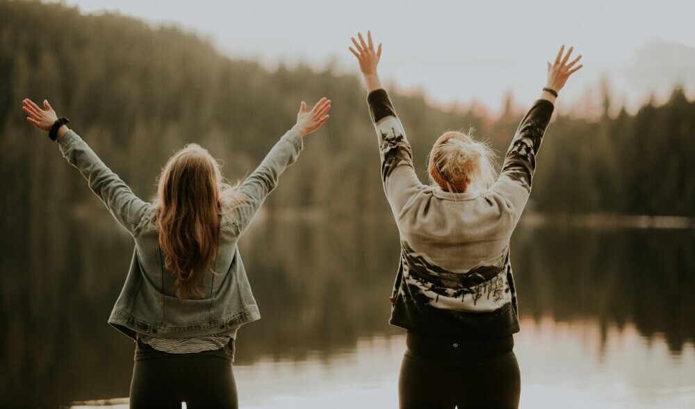 Two women with the backs to the camera, holding their arms in the air in celebration
