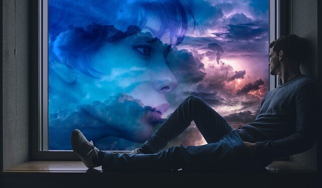 man sitting on windowsill looking out at a woman's face as if lucid dreaming