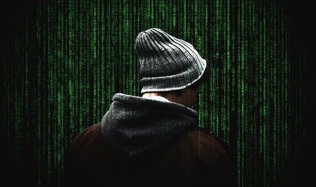 a man in a coat and hat looking at matrix-like screen where green numbers and symbols are cascading down