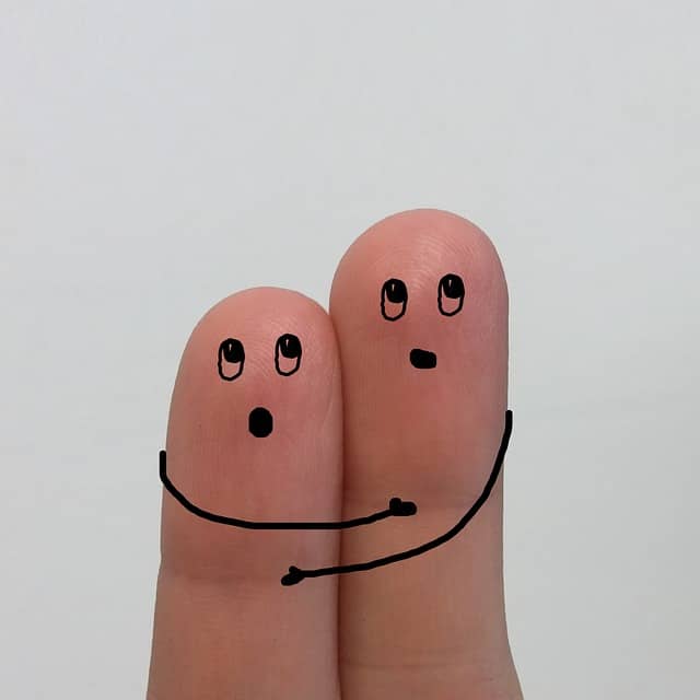 First two fingers of a person's hand  with hand drawn arms and faces to represent tapping and EFT