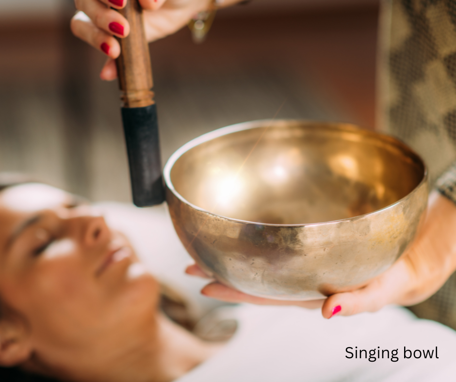Woman lying on a therapist couch and another person playing a singing bowl in the foreground